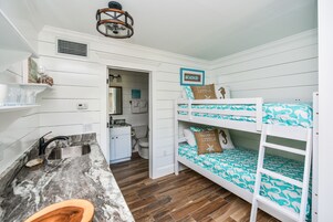 A compact room with a bunk bed, a sink, and a small kitchenette.
