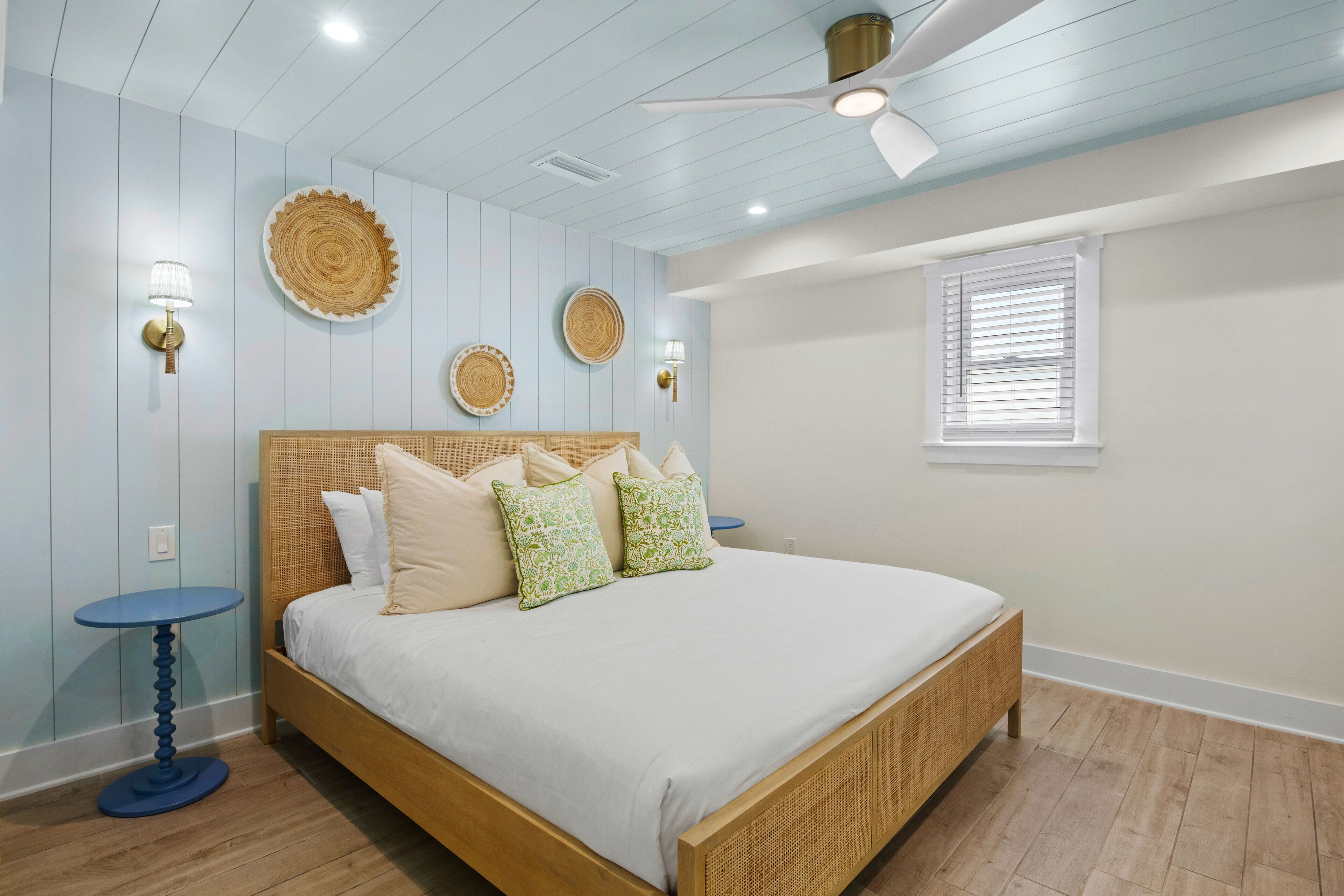 A bedroom with a wooden bed, light blue walls, and a ceiling fan.