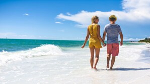 A couple walking on a beach with clear skies and ocean waves. - Tropical Breeze Resort (Siesta Key)