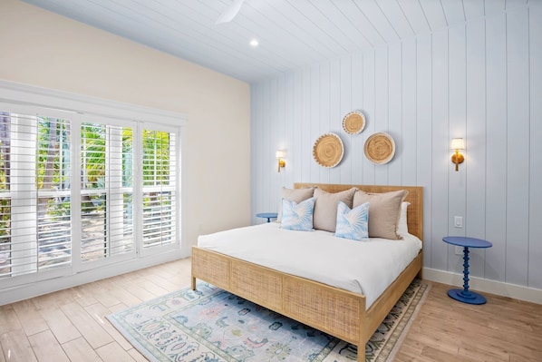 Un dormitorio con una cama grande, dos lámparas fijadas a la pared y vistas al exterior por la ventana.