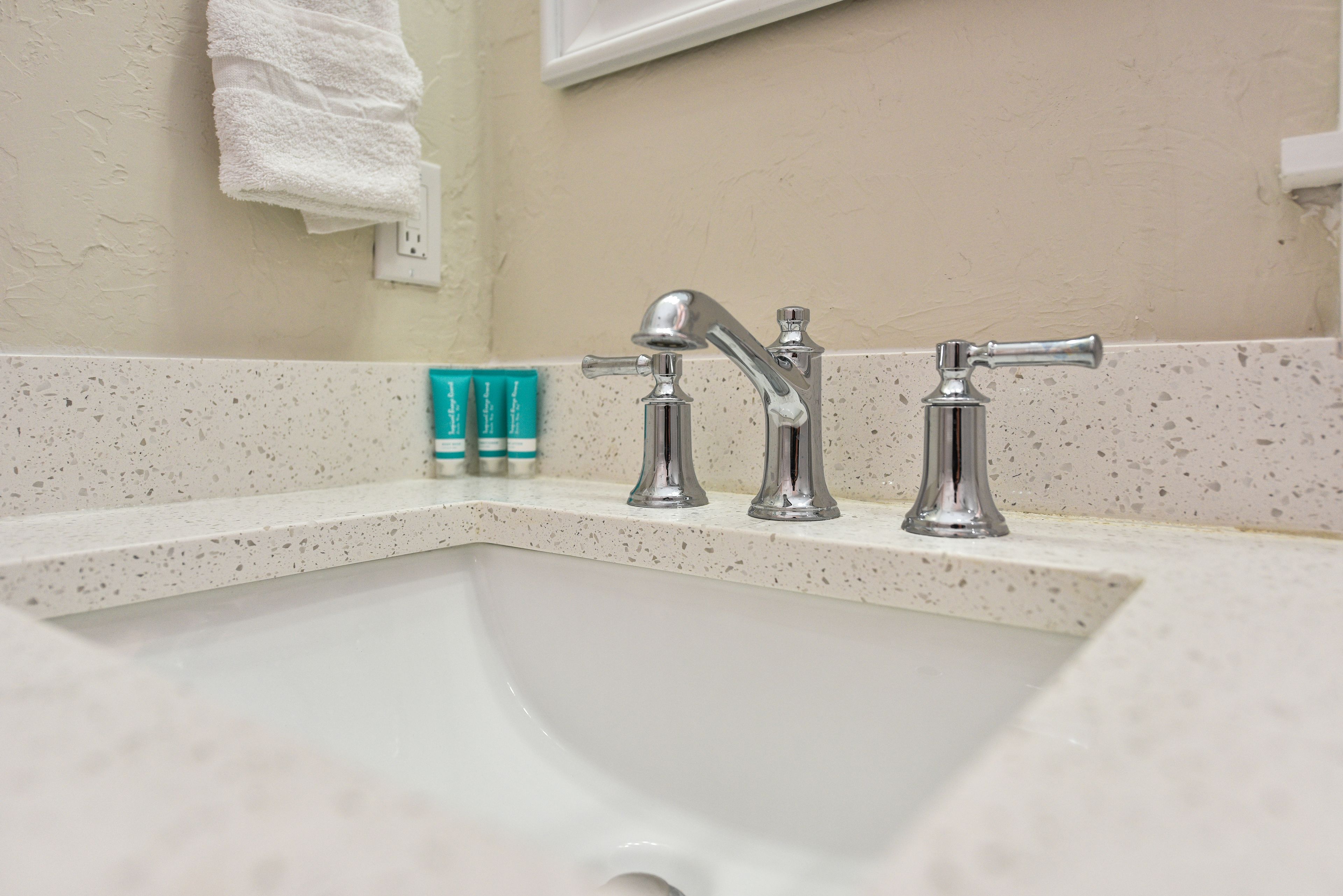 A bathroom sink with two faucets and a towel hanging on the wall.