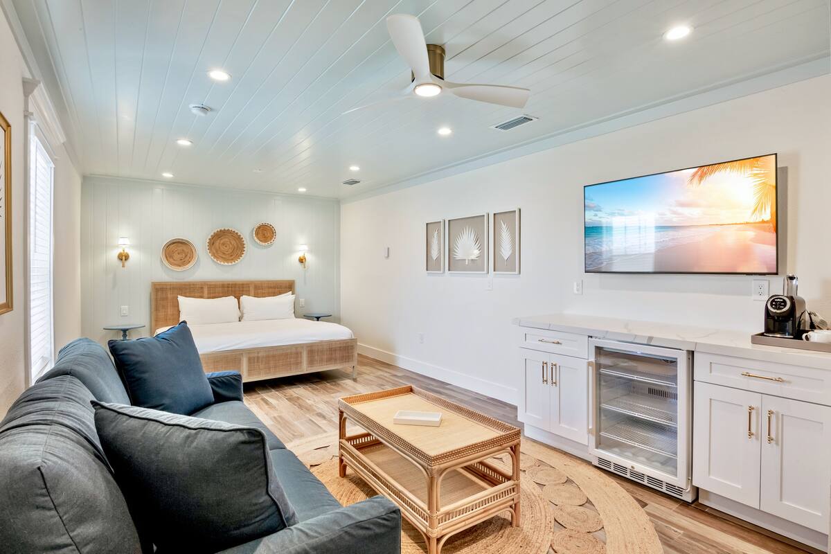 A modern living room with a sofa, coffee table, and a bed with a headboard.
