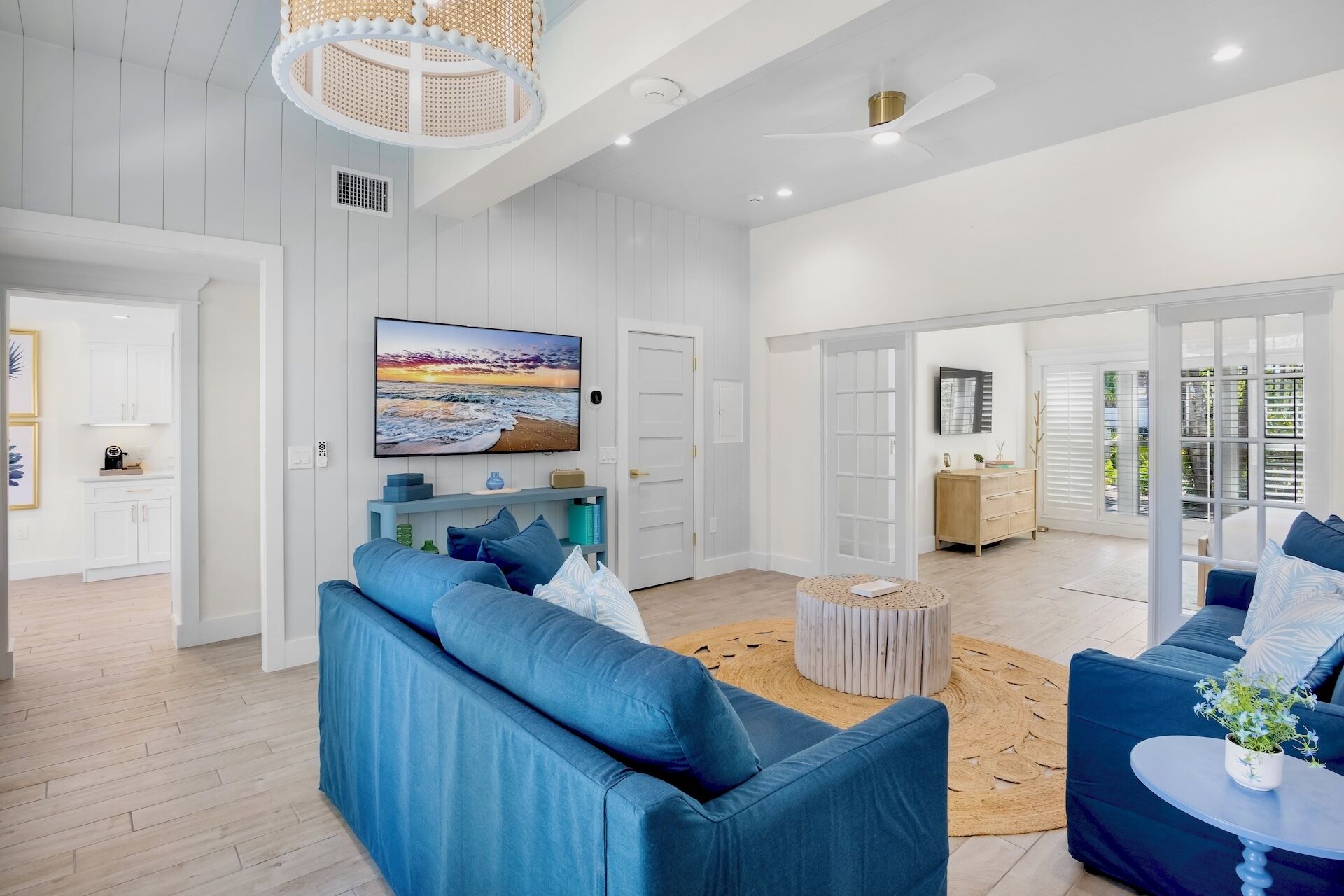 A spacious living room with a large blue sofa, a round coffee table, and a television mounted on the wall.