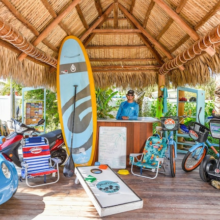 A beachside rental area with surfboards, a paddleboard, a beach ball, and a rental car.