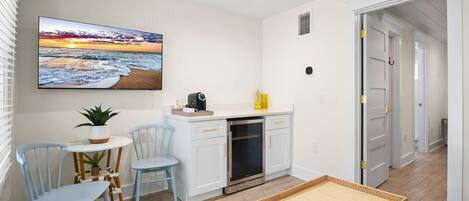 A compact kitchen with white cabinets, a built-in oven, and a small dining area with two chairs and a table.