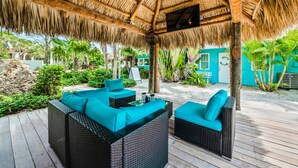 An outdoor patio with wicker furniture and a thatched roof. - Tropical Breeze Resort (Siesta Key)