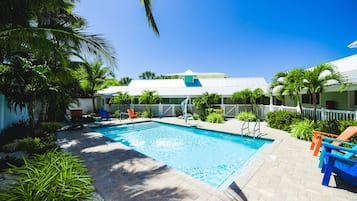 Relax by the pool surrounded by lush greenery and palm trees.