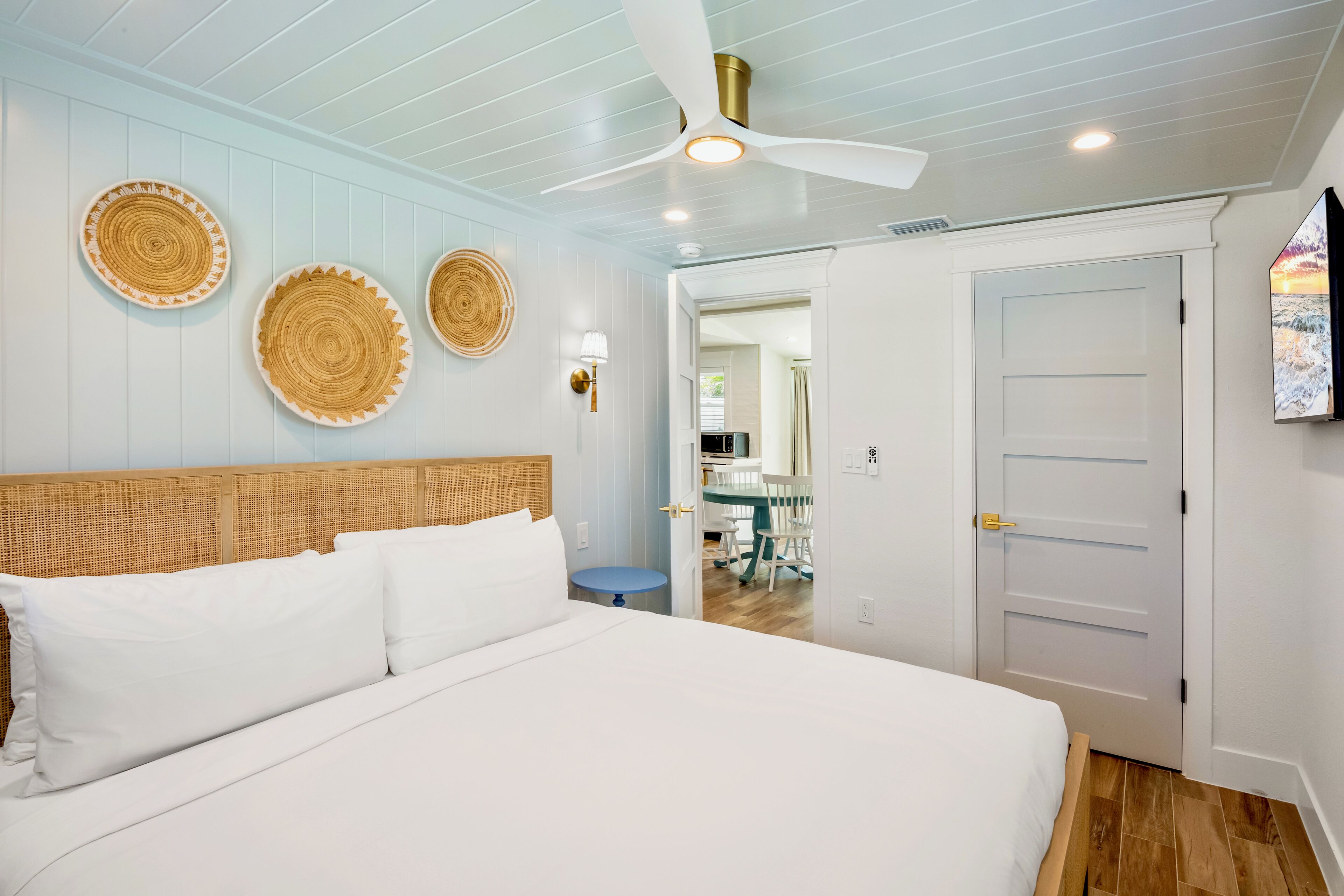 Ein Schlafzimmer mit Bett, Deckenventilator und wandmontierten Korbwägelchen.