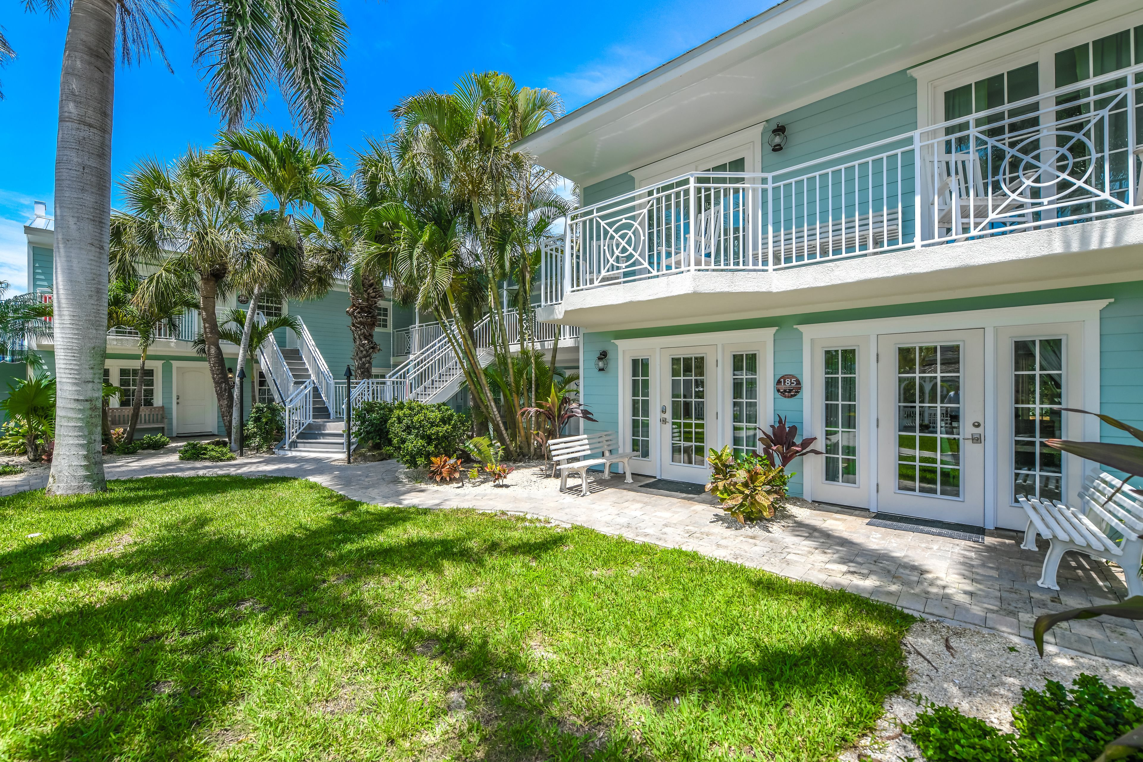 A two-story building with a balcony, a staircase, and a well-maintained lawn.