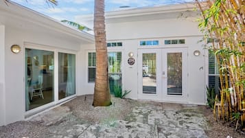 Una casa moderna con un porche cubierto, ventanas grandes y un letrero con el número 114.