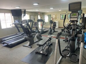 Un gimnasio con cintas de correr, máquinas elípticas y equipo de pesas.