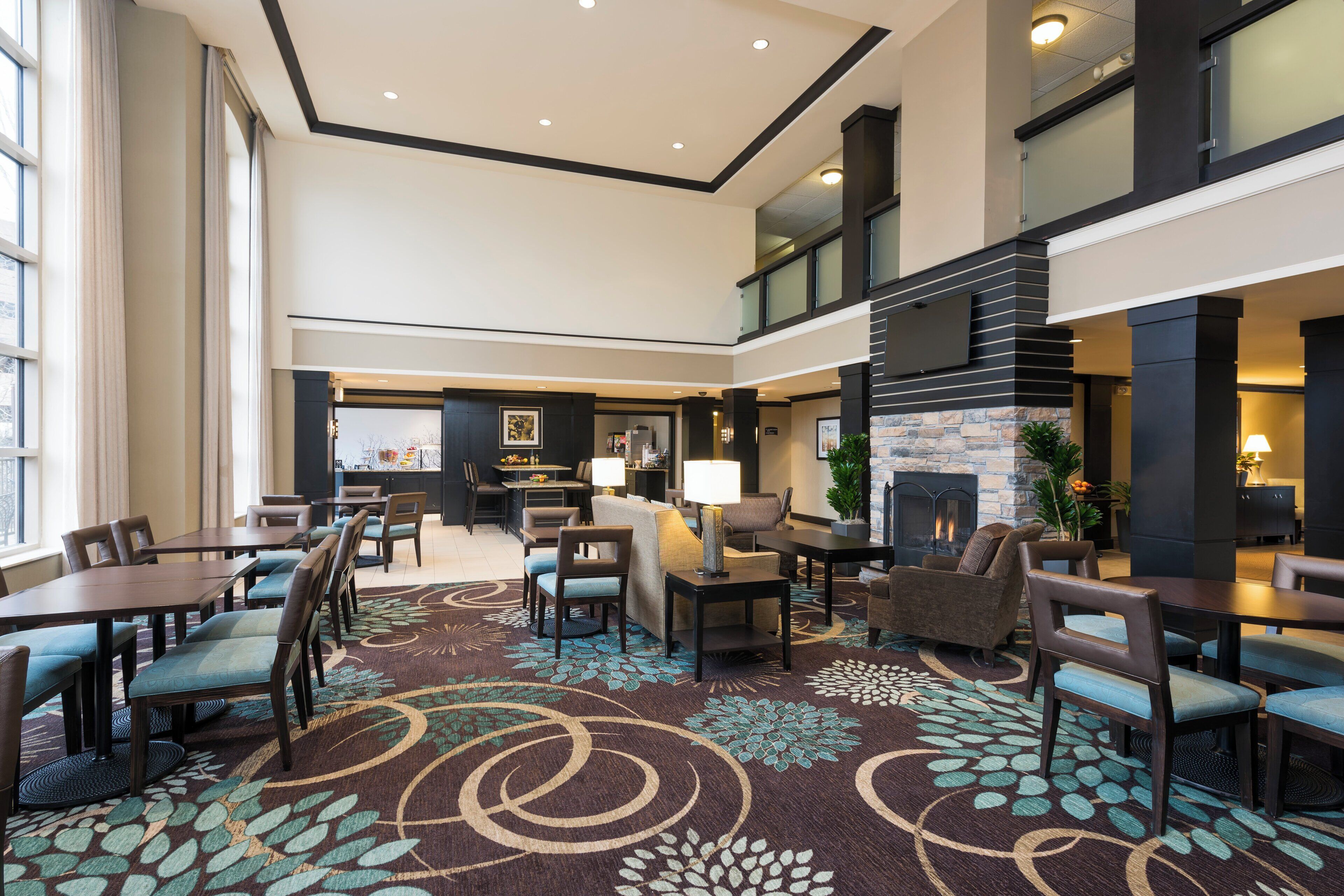 Un hall de hotel con zona de comedor, disposición de asientos y chimenea.
