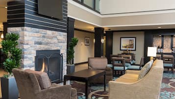 A lobby with a stone fireplace, seating area, and a coffee station.