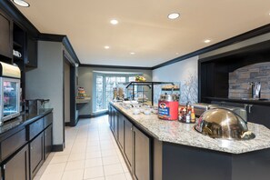 A modern kitchen with a granite countertop, a Quaker Oatmeal dispenser, and a stone backsplash. - Staybridge Suites Chicago-Oakbrook Terrace by IHG (Villa Park)