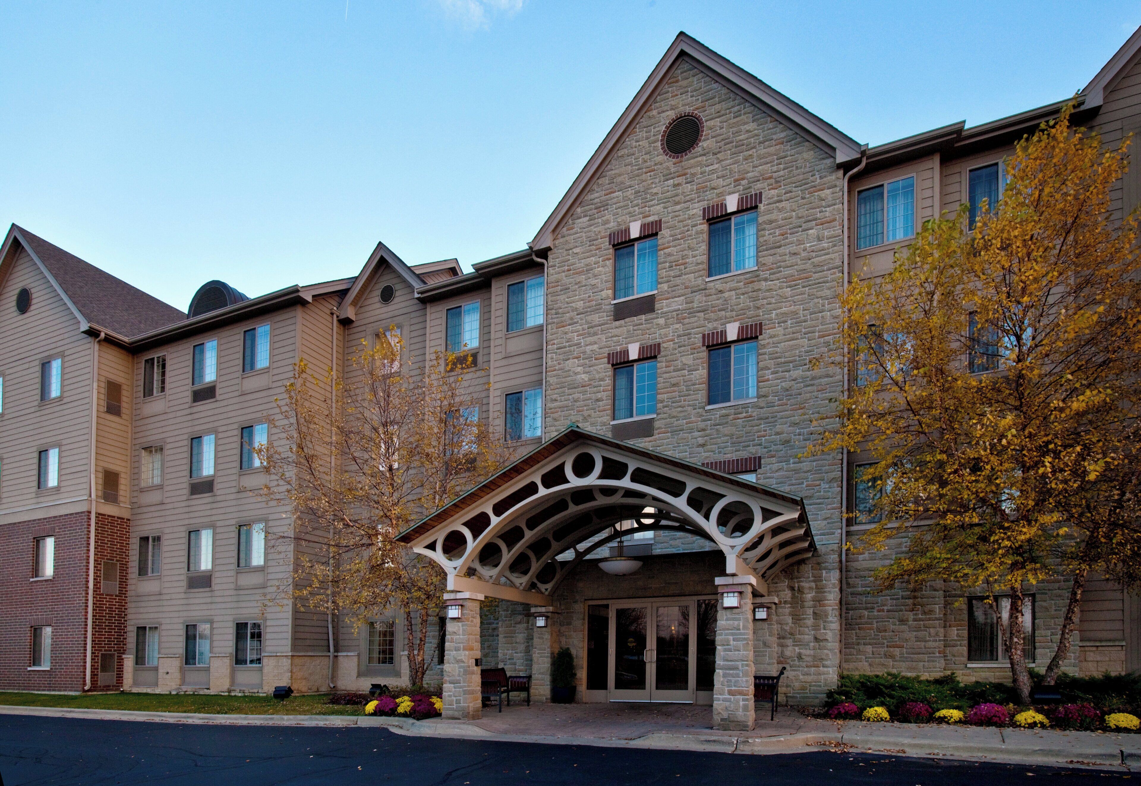 A multi-story hotel with a stone facade, a covered entrance, and a parking lot.