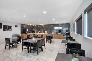 Un comedor moderno con suelo de mármol, sillas negras y una zona de bar central con un revestimiento blanco y negro.