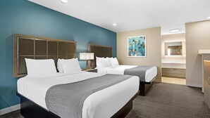 Ein Hotelzimmer mit zwei Betten, einem großen Gemälde an der Wand und einem durchgegangenen Tür sichtbaren Badezimmer.
