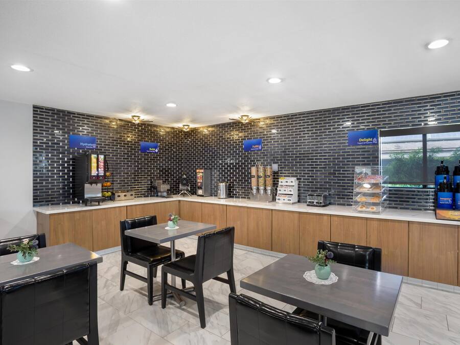 A modern kitchen with a brick backsplash, wooden cabinets, and a counter with various appliances and food items.