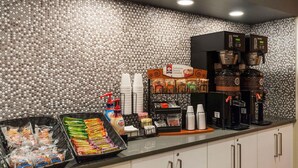A breakfast bar with coffee machines, a variety of packaged foods, and a coffee dispenser.