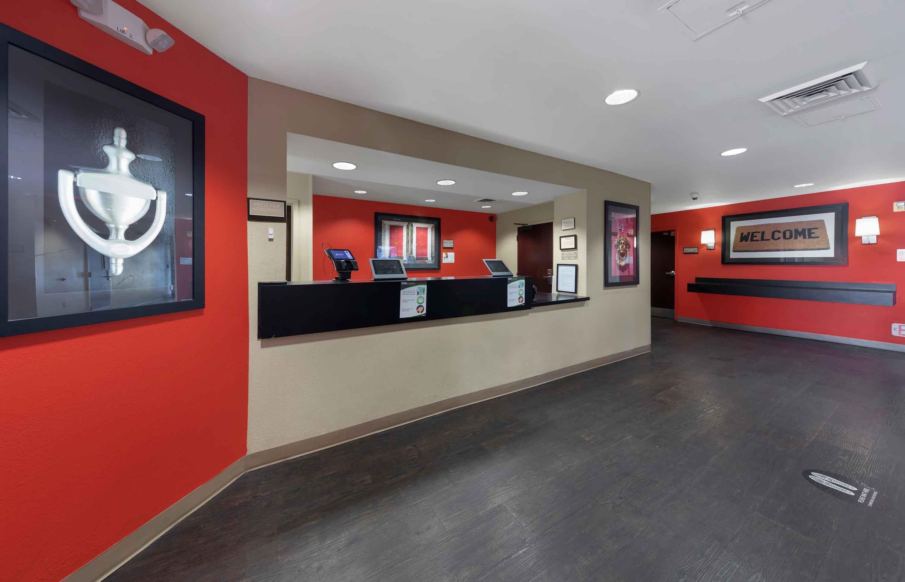 A reception area with a red and beige color scheme, a welcome sign, and a reception desk with two computers.