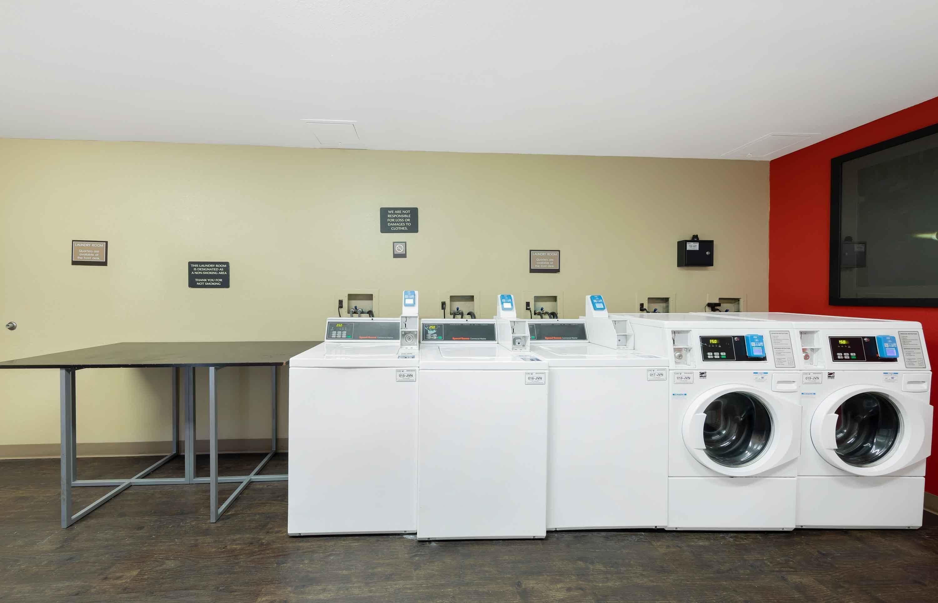A laundry room with multiple washing machines and a table.