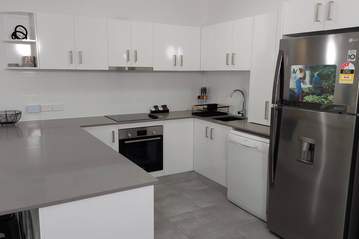 A modern kitchen with white cabinets, stainless steel appliances, and a grey countertop.