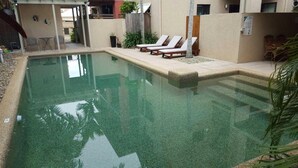 A swimming pool with lounge chairs and a small patio area. - Nautilus Holiday Apartments (Port Douglas)
