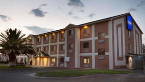 Een hotel met meerdere verdiepingen, een bakstenen gevel, veel ramen en een goed verlichte ingang.