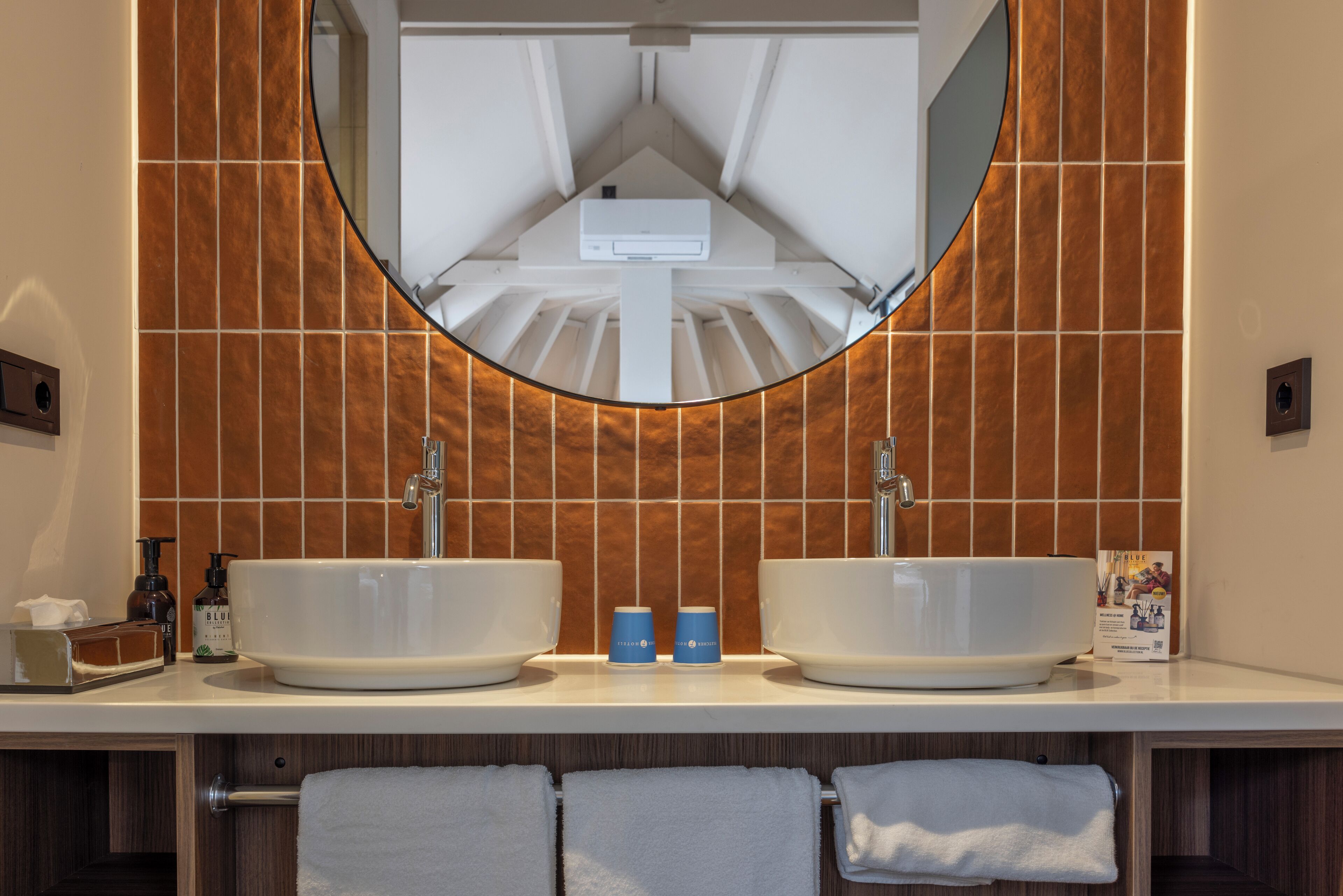 A bathroom with two sinks, a large mirror, and wooden paneling on the walls.