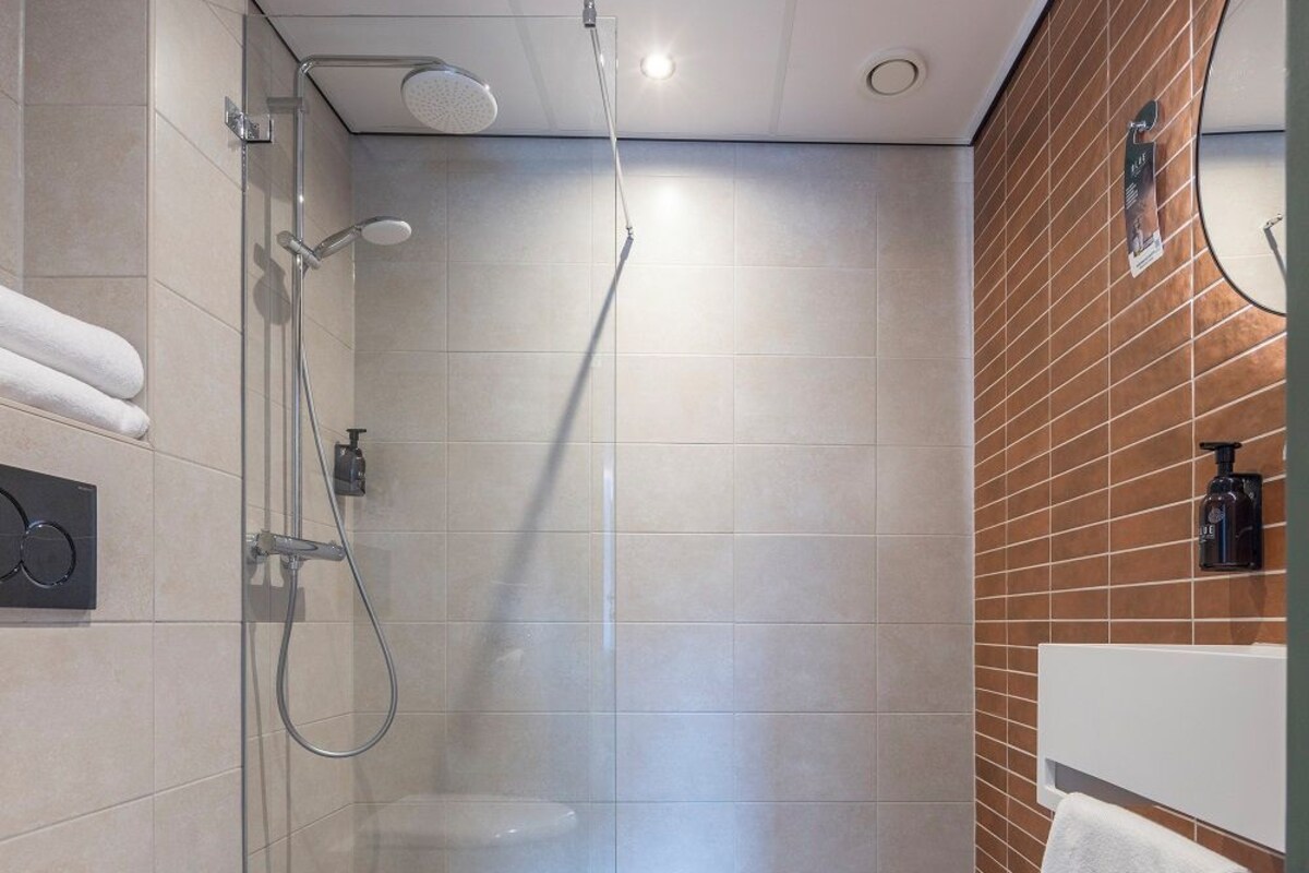 A modern bathroom with a toilet, shower, and a vanity with a mirror.