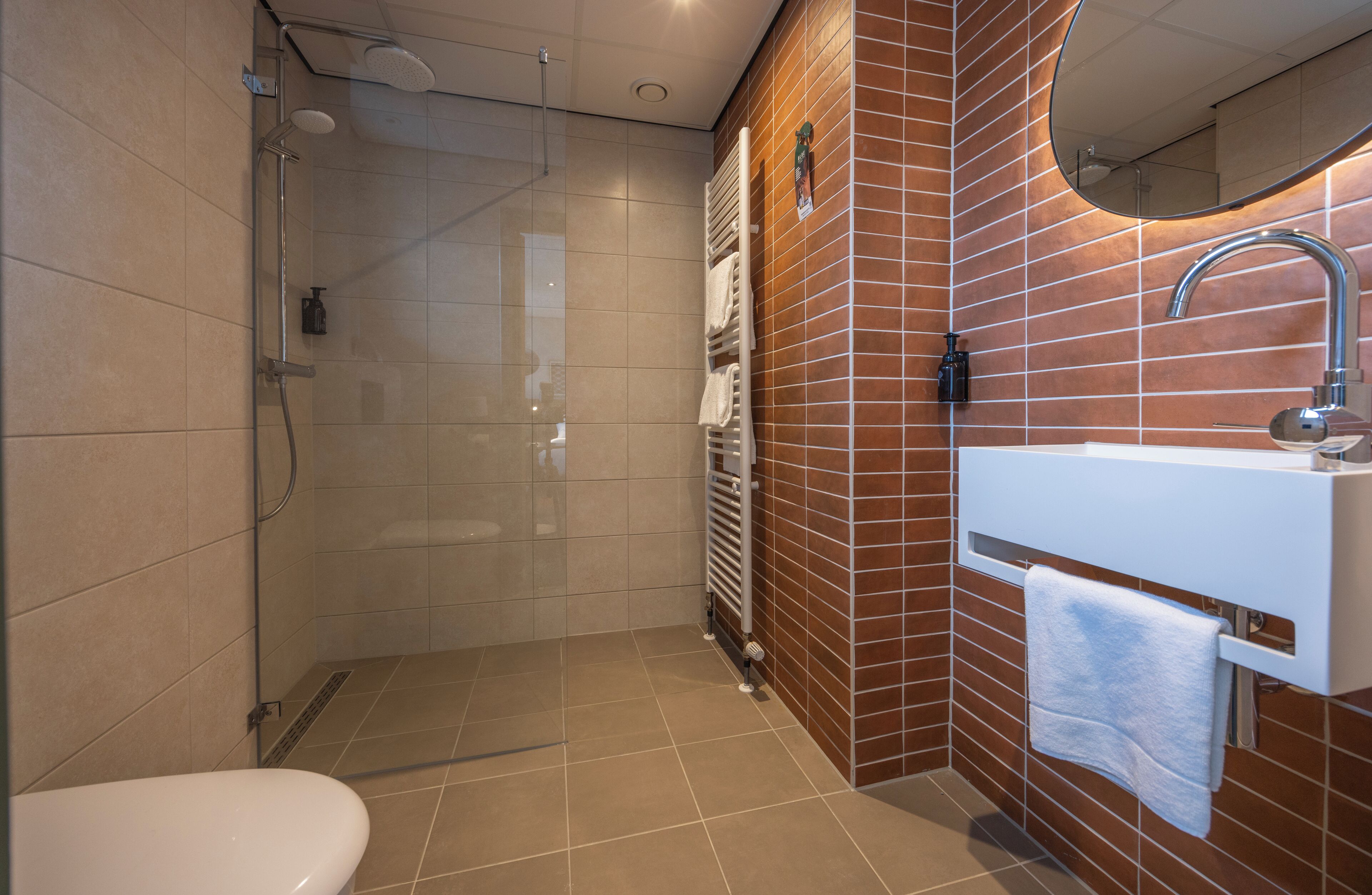 A modern bathroom with a shower, toilet, and sink.