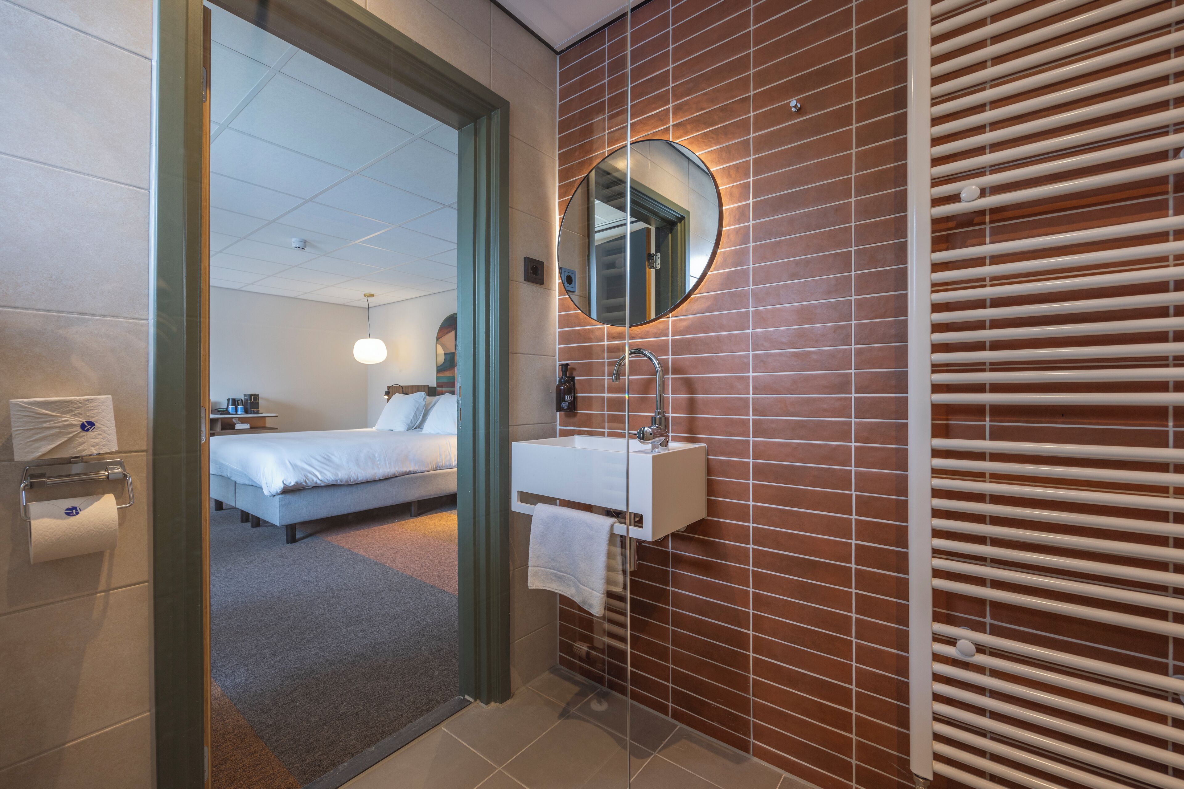 A hotel bathroom with a sink, mirror, and towel rack.