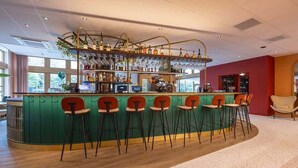 Zona de bar con una barra curva, varios taburetes y una variedad de botellas y vasos.