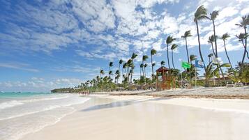 Aan een privéstrand, wit zand, ligstoelen, parasols