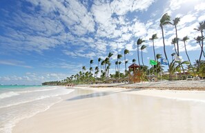 Playa privada, arena blanca, sillas reclinables de playa, sombrillas
