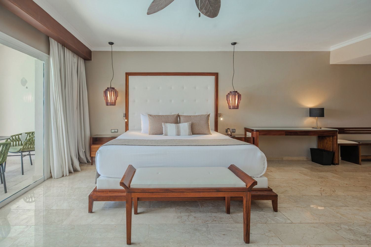 A hotel room with a large bed, bedside tables, a desk, and a view of the outdoors.