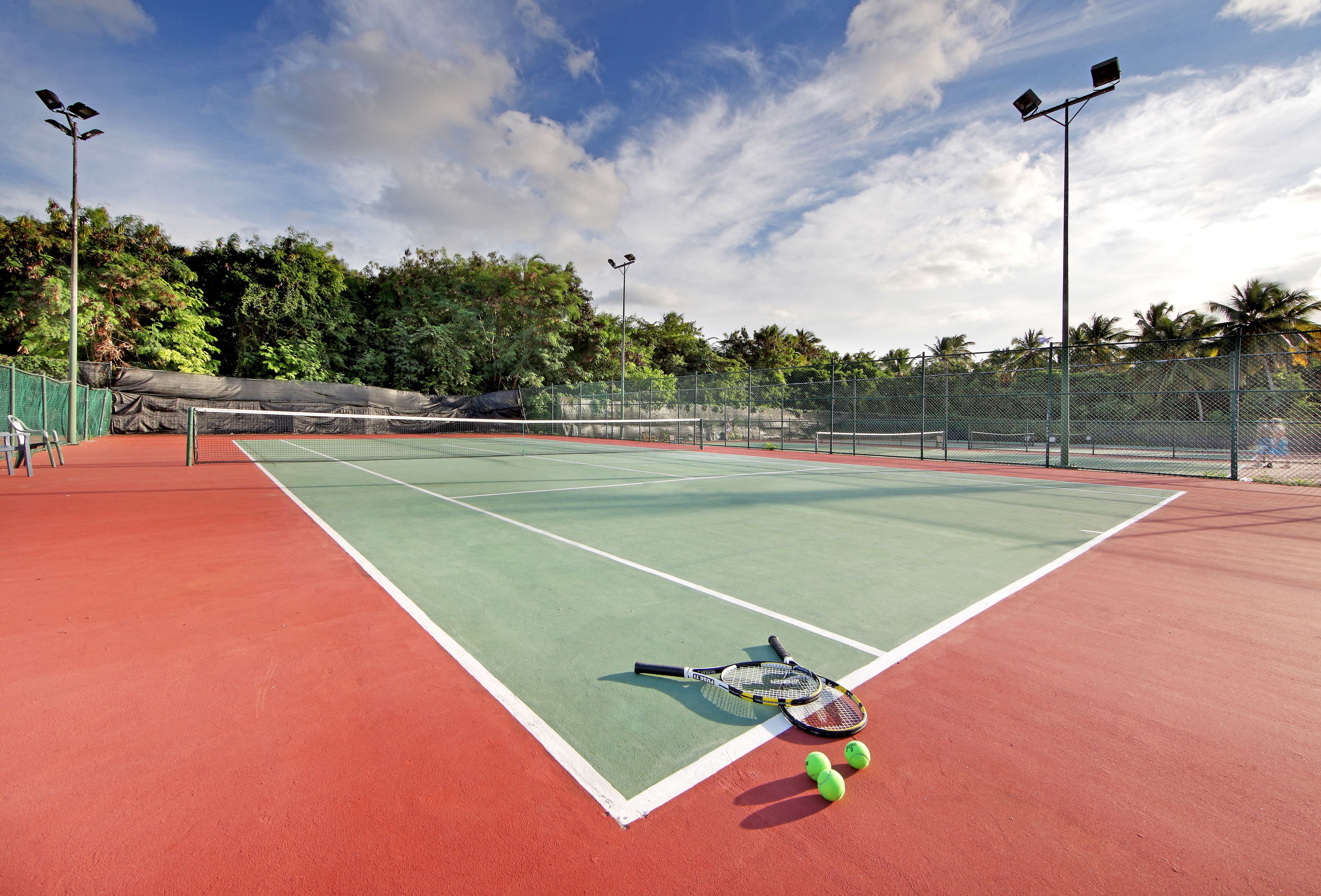 Una cancha de tenis con dos raquetas y tres pelotas.