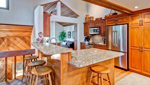 A kitchen with wooden cabinets, a stainless steel refrigerator, and a granite countertop. - Ridgepoint Townhomes by East West Hospitality (Avon)