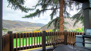 A covered patio with a view of a green field and mountains. - Ridgepoint Townhomes by East West Hospitality (Avon)