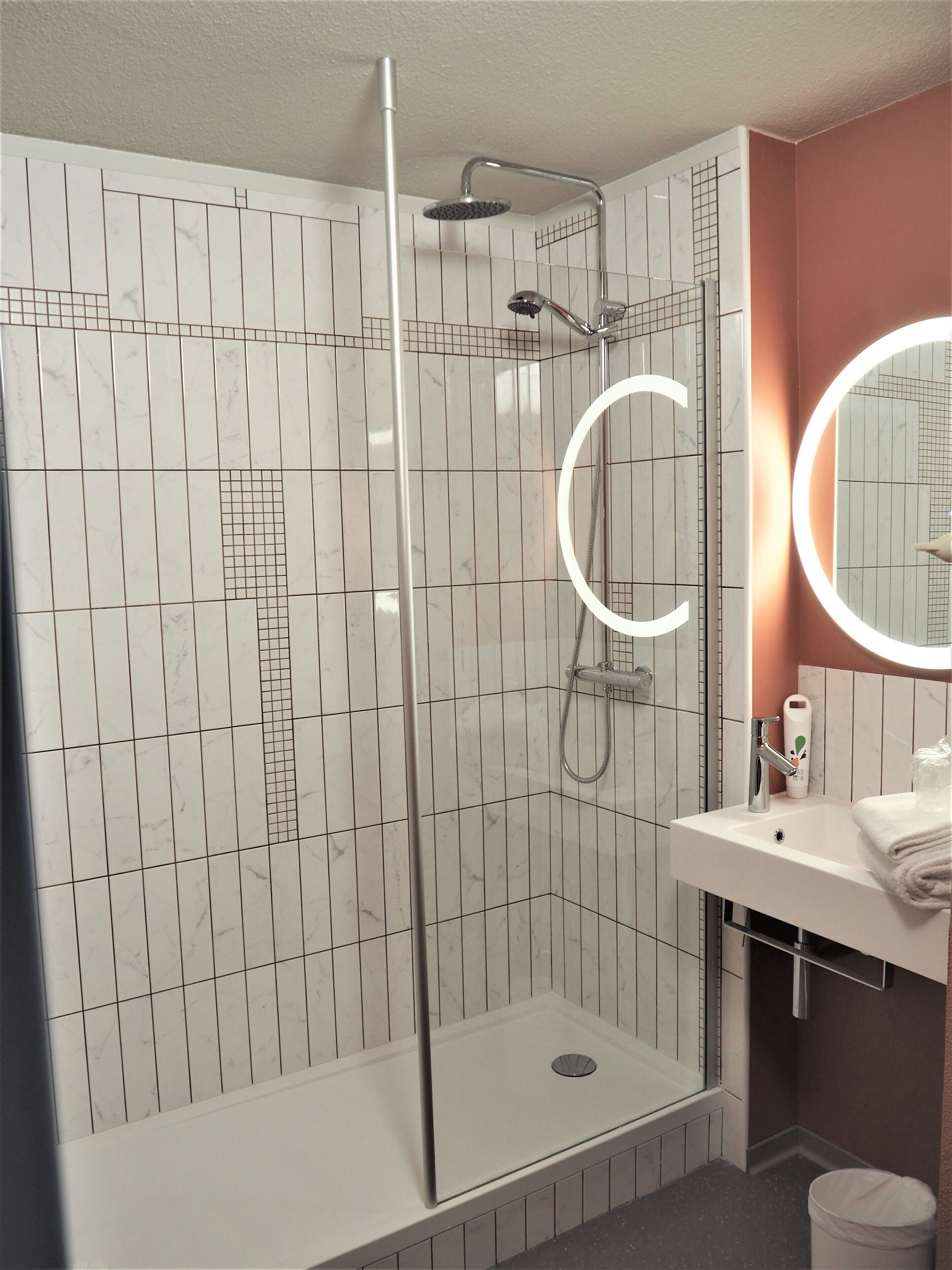 Een moderne badkamer met een douchecabine van glas, een witte wastafel met spiegel en een toilet.