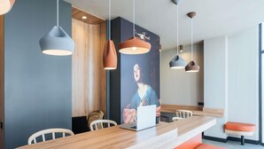 Un comedor moderno con una mesa de madera, asientos color naranja e iluminación colgante.