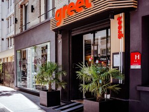 Un edificio con un letrero que dice 'greet', una mesa de recepción y un letrero con la letra 'H' que indica un hotel.