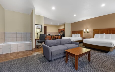 A hotel room with a sofa, a bed, a desk, a chair, a lamp, and a bathroom with a bathtub.