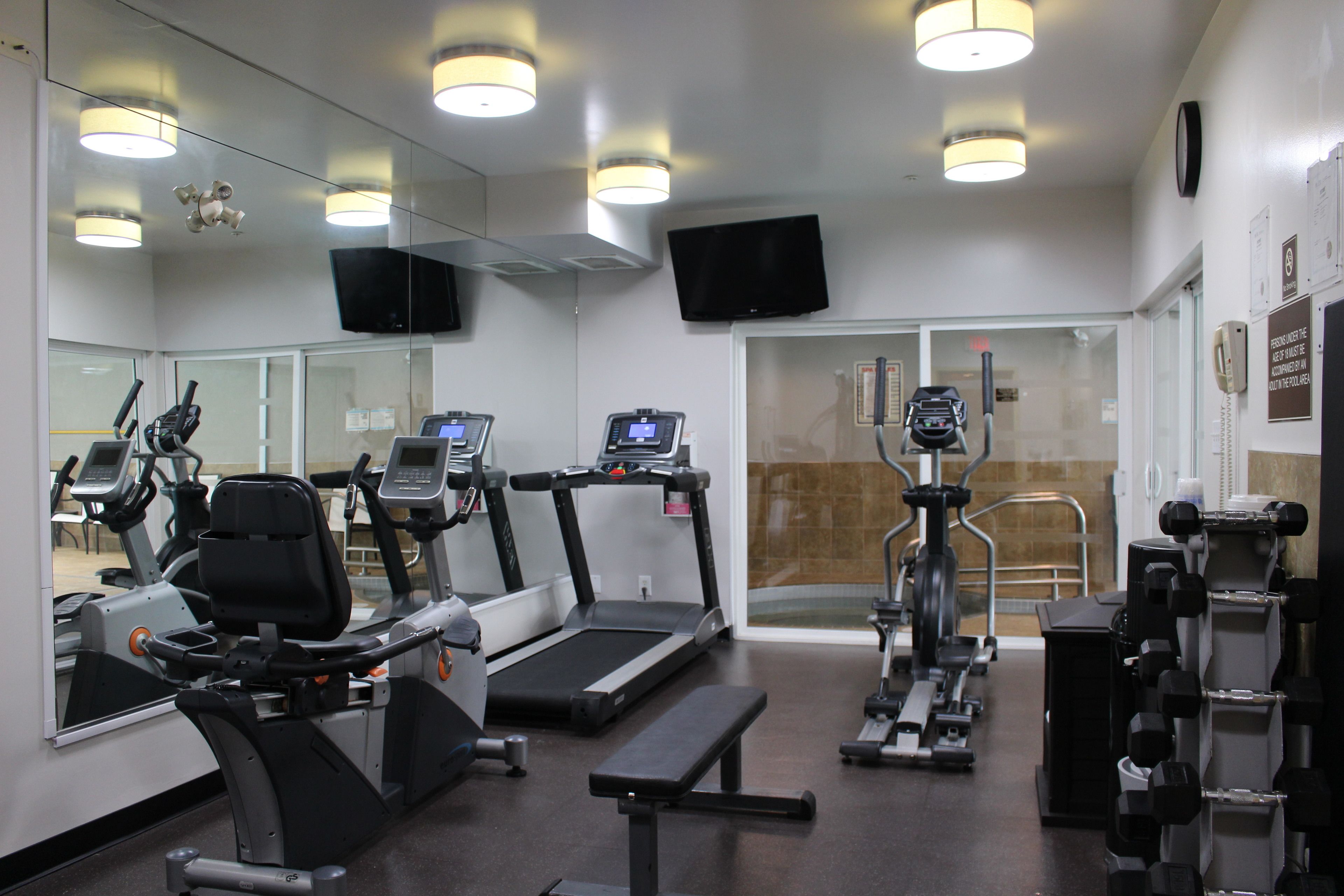 A gym with treadmills, elliptical machines, and weight equipment.
