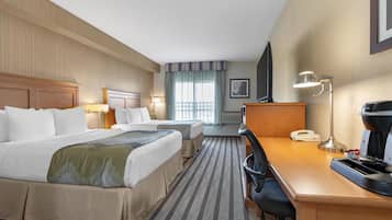 Une chambre d’hôtel avec deux lits, un bureau doté d’un téléphone et d’une machine à café, une chaise et un téléviseur.