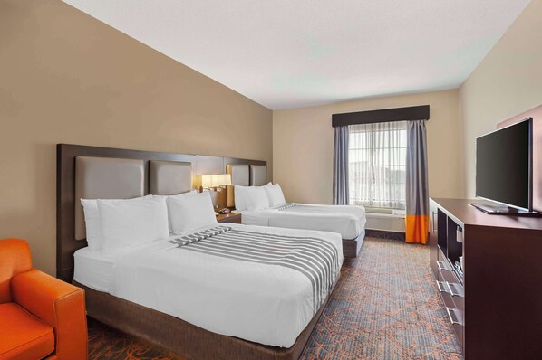 A hotel room with two beds, a television, a desk, and a window with curtains. - Best Western Plus Executive Inn (Toronto)