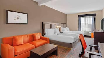 A hotel room with a large bed, a sofa, a desk, and a chair.