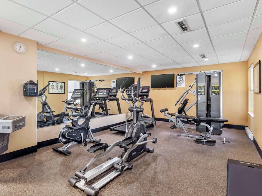 Un gimnasio con equipos de ejercicio variados, incluyendo cintas de correr, elípticas y máquinas de pesas.
