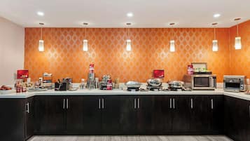 A modern kitchen with dark cabinets, a white countertop, and various appliances including a microwave, toaster, and coffee maker.