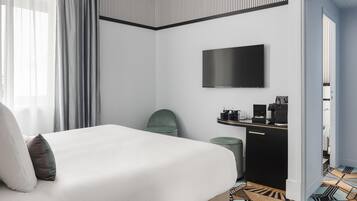 Une chambre d’hôtel avec un lit, une télévision, un bureau avec une machine à café et un sol à motifs.